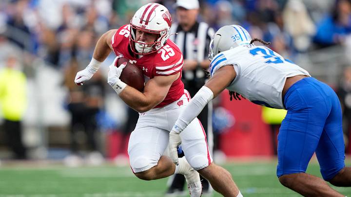 Sep 6, 2025; Madison, Wisconsin, USA;  Wisconsin Badgers running back Cade Yacamelli (25) runs the ball against Middle Tennessee Blue Raiders linebacker Muaaz Byard (35) during the second half at Camp Randall Stadium. Mandatory Credit: Kayla Wolf-Imagn Images
