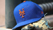 Jul 13, 2022; Atlanta, Georgia, USA; A detailed view of a New York Mets hat and glove in the dugout against the Atlanta Braves in the eighth inning at Truist Park. 