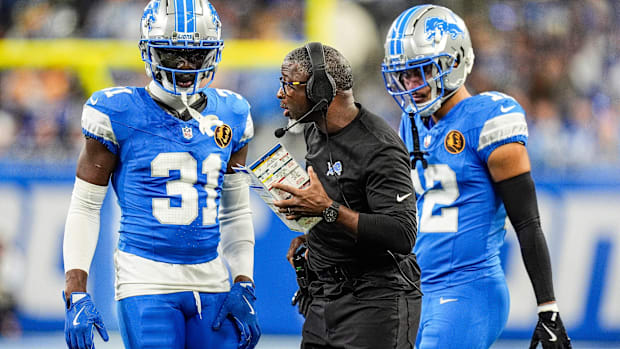 Detroit Lions defensive coordinator Aaron Glenn talks to safeties Kerby Joseph (31), left, and Brian Branch (32) 