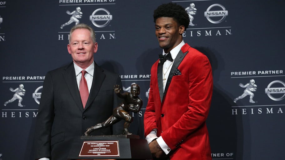Louisville quarterback Lamar Jackson and head coach Bobby Petrino pose with the Heisman Trophy in 2016.