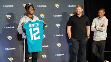 The Jacksonville Jaguars first-round pick, Colorado Buffaloes wide receiver and defensive back Travis Hunter, left, poses with his jersey during a press conference Friday, March 25, 2025 at Miller Electric Center in Jacksonville, Fla. as Head Coach Liam Coen, center and General Manager James Gladstone, right, watch. [Doug Engle/Florida Times-Union]