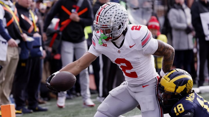 Nov 25, 2023; Ann Arbor, Michigan, USA; Ohio State Buckeyes wide receiver Emeka Egbuka (2) is hit by Michigan Wolverines defensive back Ja'Den McBurrows (18) as he scores a touchdown in the first half against the Michigan Wolverines at Michigan Stadium. Mandatory Credit: Rick Osentoski-USA TODAY Sports