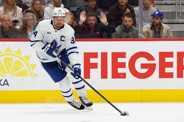 Hockey player in white uniform skates with the puck