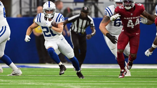 Colts running back Evan Hull (all-white uniform with blue trim) looks for more room to run downfield.