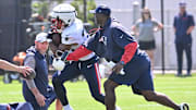 Coaching staff tries to punch the ball away from  New England Patriots running back TreVeyon Henderson during training camp