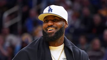 Oct 5, 2025; San Francisco, California, USA;  Los Angeles Lakers forward LeBron James (23), wearing a Los Angeles Dodgers hat, watches from the sideline during a break against the Golden State Warriors in the third quarter at Chase Center. Mandatory Credit: David Gonzales-Imagn Images