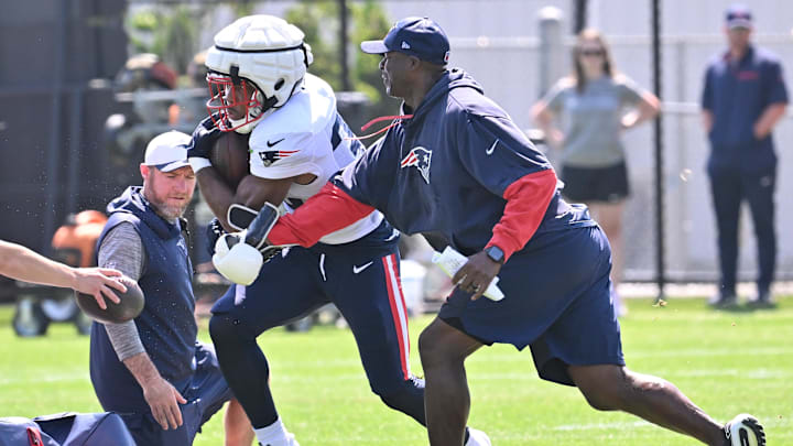 Coaching staff tries to punch the ball away from New England Patriots running back TreVeyon Henderson during training camp Coaching staff tries to punch the ball away from New England Patriots running back TreVeyon Henderson during training camp