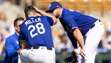 Feb 20, 2025; Phoenix, Arizona, USA; Los Angeles Dodgers pitcher Bobby Miller (28) talks to Max Muncy as he is tended to by a trainer after being hit in the head with a line drive against the Chicago Cubs during a spring training game at Camelback Ranch-Glendale. Mandatory Credit: Mark J. Rebilas-Imagn Images
