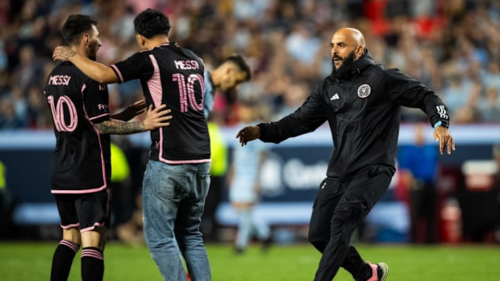 Apr 13, 2024; Kansas City, Missouri, USA; Bodyguard Yassine Chueko removes a pitch invader from Inter Miami CF forward Lionel Messi (10) during the second half against Sporting Kansas City at Arrowhead Stadium. Mandatory Credit: Jay Biggerstaff-Imagn Images Apr 13, 2024; Kansas City, Missouri, USA; Bodyguard Yassine Chueko removes a pitch invader from Inter Miami CF forward Lionel Messi (10) during the second half against Sporting Kansas City at Arrowhead Stadium. Mandatory Credit: Jay Biggerstaff-Imagn Images