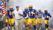 Sep 27, 2025; Pittsburgh, Pennsylvania, USA;  Pittsburgh Panthers head coach Pat Narduzzi (white) and tight end Jake Overman (87) lead the team onto the field to play the Louisville Cardinals at Acrisure Stadium. Mandatory Credit: Charles LeClaire-Imagn Images