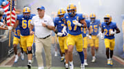 Sep 27, 2025; Pittsburgh, Pennsylvania, USA;  Pittsburgh Panthers head coach Pat Narduzzi (white) and tight end Jake Overman (87) lead the team onto the field to play the Louisville Cardinals at Acrisure Stadium. Mandatory Credit: Charles LeClaire-Imagn Images