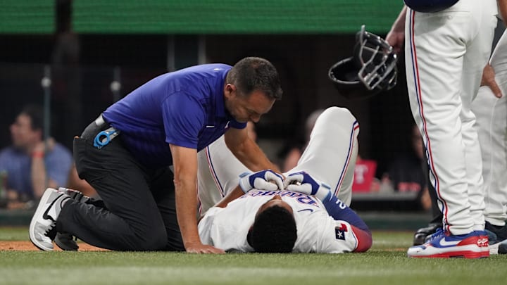 Jul 26, 2025; Arlington, Texas, USA; Texas Rangers second baseman Marcus Semien (2) is checked out by trainer Matt Lucero, as he lays on the ground after being hit by a pitch during the third inning against the Atlanta Braves at Globe Life Field. Jul 26, 2025; Arlington, Texas, USA; Texas Rangers second baseman Marcus Semien (2) is checked out by trainer Matt Lucero, as he lays on the ground after being hit by a pitch during the third inning against the Atlanta Braves at Globe Life Field.