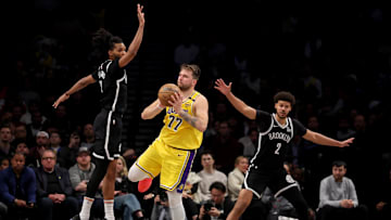 Mar 10, 2025; Brooklyn, New York, USA; Los Angeles Lakers guard Luka Doncic (77) looks to pass the ball against Brooklyn Nets forwards Ziaire Williams (8) and Cameron Johnson (2) during the fourth quarter at Barclays Center. Mandatory Credit: Brad Penner-Imagn Images