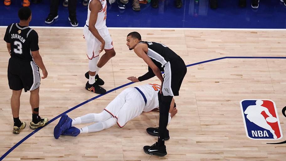 San Antonio Spurs forward Victor Wembanyama acknowledges New York Knicks center Karl-Anthony Towns, who lies on the court.