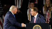 President Donald Trump shakes hands with legendary Alabama football coach Nick Saban before delivering a special commencement address to University of Alabama graduates.