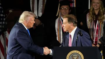 President Donald Trump shakes hands with legendary Alabama football coach Nick Saban before delivering a special commencement address to University of Alabama graduates.