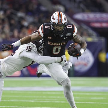 Dec 27, 2023; Houston, TX, USA; Oklahoma State Cowboys running back Ollie Gordon II (0) runs with the ball as Texas A&M Aggies defensive lineman Rylan Kennedy (15) attempts to make a tackle during the third quarter at NRG Stadium. Mandatory Credit: Troy Taormina-USA TODAY Sports