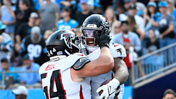 Oct 13, 2024; Charlotte, North Carolina, USA; Atlanta Falcons running back Bijan Robinson (7) celebrates with guard Ryan Neuzil (64) after scoring a touchdown in the first quarter at Bank of America Stadium. Mandatory Credit: Bob Donnan-Imagn Images