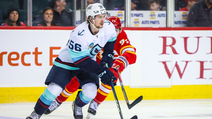 Dec 27, 2023; Calgary, Alberta, CAN; Seattle Kraken right wing Kailer Yamamoto (56) controls the puck against Calgary Flames right wing Walker Duehr (71) during the second period at Scotiabank Saddledome. Mandatory Credit: Sergei Belski-USA TODAY Sports