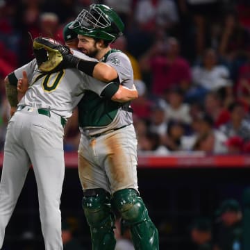 Jul 26, 2024; Anaheim, California, USA; Oakland Athletics pitcher Lucas Erceg (70) and catcher Shea Langeliers (23) celebrate the victory against the Los Angeles Angels at Angel Stadium. Mandatory Credit: Gary A. Vasquez-USA TODAY Sports