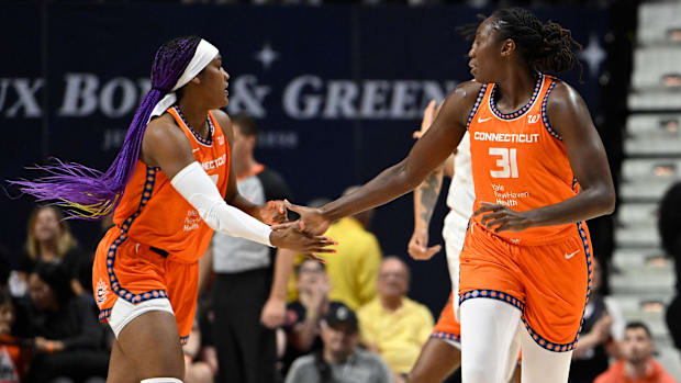 Connecticut Sun center Tina Charles and forward Aaliyah Edwards celebrate after scoring, wearing orange jerseys. 