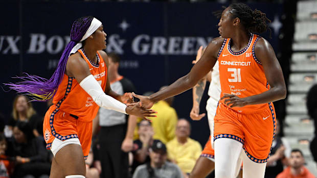 Connecticut Sun center Tina Charles and forward Aaliyah Edwards celebrate a basket, wearing orange jerseys. 