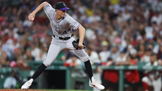 Herget throwing a ball out of a black glove wearing a grey uniform with black numbers and long black sock
