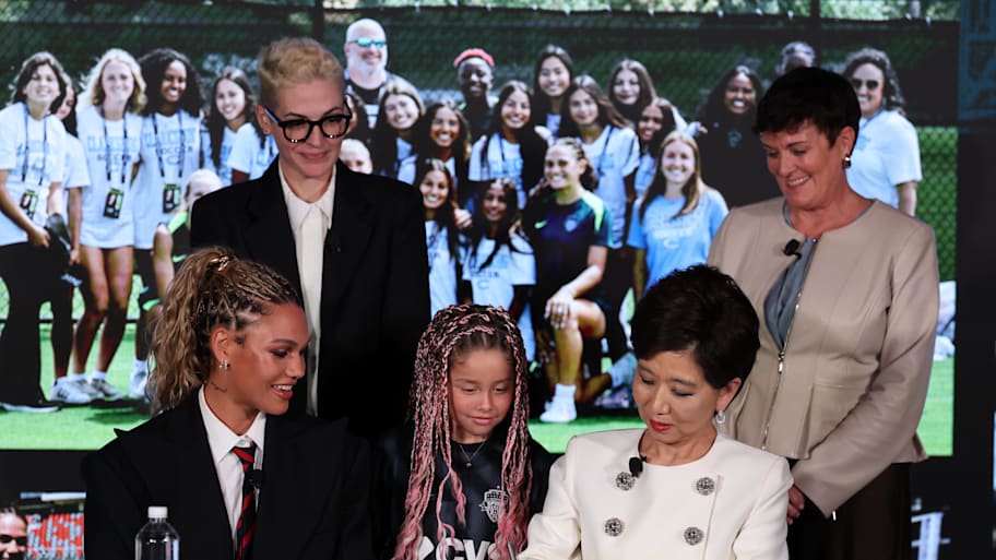 Trinity Rodman of the Washington Spirit watches team owner Michele Kang (front right) signs a contract extension