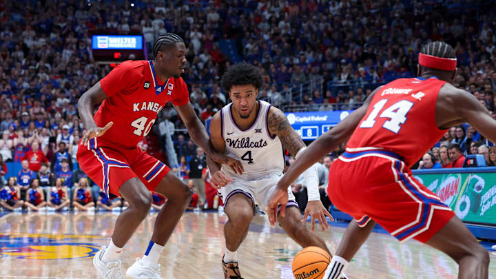 Mar 7, 2026; Lawrence, Kansas, USA; Kansas State Wildcats guard P.J. Haggerty (4) dribbles between Kansas Jayhawks forward Flory Bidunga (40) and guard Melvin Council Jr. (14) during the first half at Allen Fieldhouse. Mandatory Credit: Scott Sewell-Imagn Images