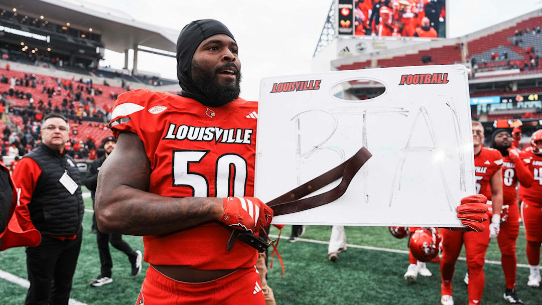 Louisville Cardinals defensive lineman Clev Lubin (50) held a coach's whiteboard with the letters BTA and carried a belt after the Cards dominated rival Kentucky 41-0 Saturday, November 29, 2025 in Louisville, Kentucky.