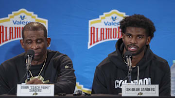Dec 28, 2024; San Antonio, TX, USA; Colorado Buffaloes head coach Deion Sanders and quarterback Shedeur Sanders (2) talk with the media after the game against the Brigham Young Cougars at Alamodome. Mandatory Credit: Troy Taormina-Imagn Images