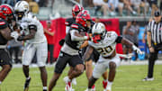 Aug 28, 2025; Orlando, Florida, USA; Jacksonville State Gamecocks running back Cam Cook (4) runs the ball as UCF Knights linebacker Lewis Carter (20) moves in during the first quarter at Acrisure Bounce House. Mandatory Credit: Mike Watters-Imagn Images