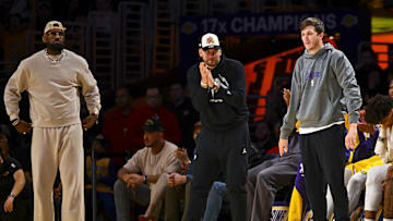 Los Angeles Lakers' LeBron James, Luka Doncic, and Austin Reaves on the sidelines against the Milwaukee Bucks.
