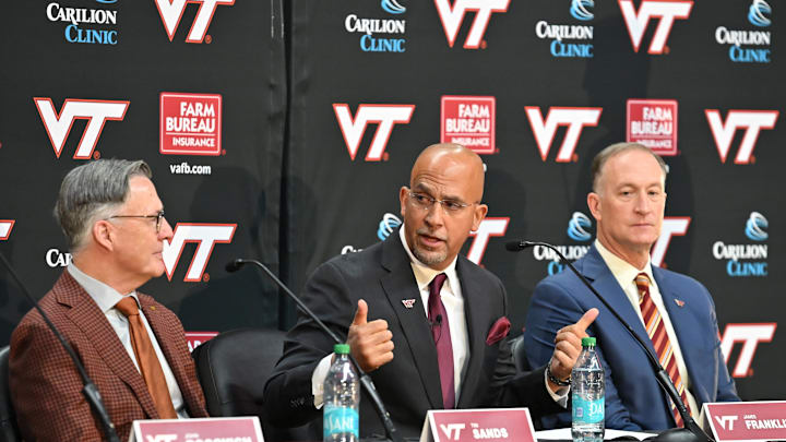 Nov 19, 2025; Blacksburg, VA, USA;  Virginia Tech head coach James Franklin (center) speaks as Virginia Tech President Timothy Sands (left) and Athletic Director Whit Babcock (right) looks on at Cassell Coliseum. Mandatory Credit: Brian Bishop-Imagn Images