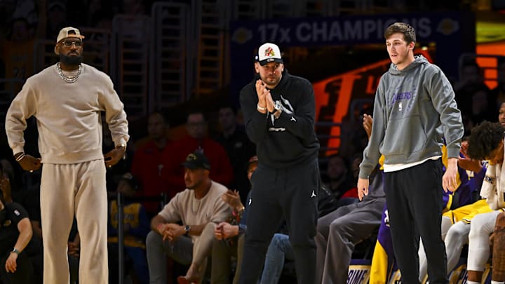 Los Angeles Lakers' LeBron James, Luka Doncic, and Austin Reaves on the sidelines against the Milwaukee Bucks.