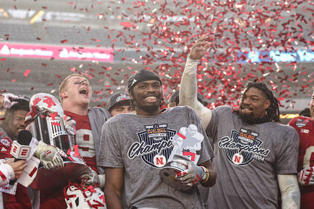 Nebraska Cornhuskers running back Rahmir Johnson (14) holds the most valuable player trophy and celebrates with teammates.