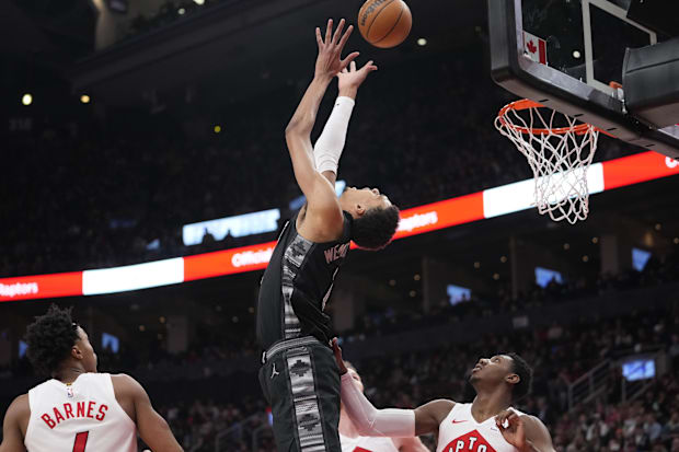 San Antonio Spurs center Victor Wembanyama (1) tries to tip a ball into the net as Toronto Raptors RJ Barrett (9) looks on.