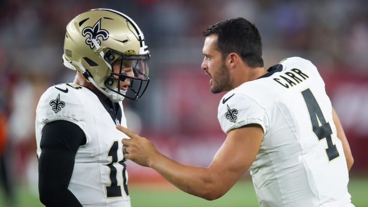 Aug 10, 2024; Glendale, Arizona, USA; New Orleans Saints quarterback Derek Carr (4) talks with Spencer Rattler (18) against the Arizona Cardinals during a preseason NFL game at State Farm Stadium. Mandatory Credit: Mark J. Rebilas-USA TODAY Sports