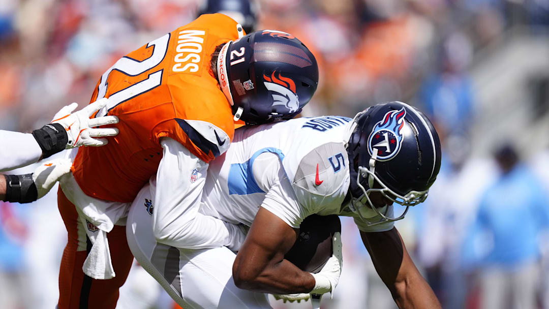 Sep 7, 2025; Denver, Colorado, USA; Denver Broncos cornerback Riley Moss (21) tackles Tennessee Titans wide receiver Elic Ayomanor (5) in the first half at Empower Field at Mile High. 