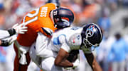 Sep 7, 2025; Denver, Colorado, USA; Denver Broncos cornerback Riley Moss (21) tackles Tennessee Titans wide receiver Elic Ayomanor (5) in the first half at Empower Field at Mile High. Mandatory Credit: Ron Chenoy-Imagn Images