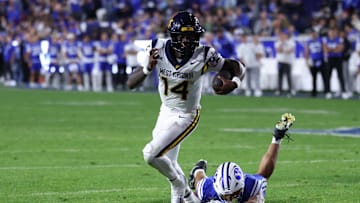 Oct 3, 2025; Provo, Utah, USA; West Virginia Mountaineers quarterback Khalil Wilkins (14) breaks a tackle by Brigham Young Cougars linebacker Siale Esera (54) during the third quarter at LaVell Edwards Stadium. Mandatory Credit: Rob Gray-Imagn Images