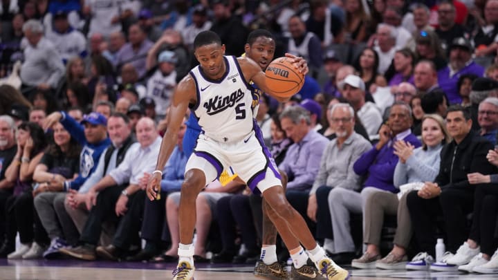 Apr 16, 2024; Sacramento, California, USA; Sacramento Kings guard De'Aaron Fox (5) dribbles the ball in front of Golden State Warriors forward Jonathan Kuminga (00) in the fourth quarter during a play-in game of the 2024 NBA playoffs at the Golden 1 Center. Mandatory Credit: Cary Edmondson-USA TODAY Sports