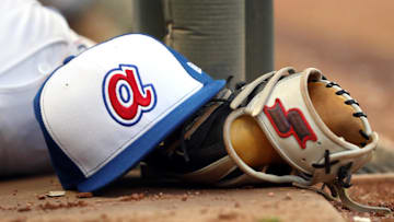 Aug 2, 2019; Atlanta, GA, USA; An Atlanta Braves throw back hat is shown with a glove in the dugout