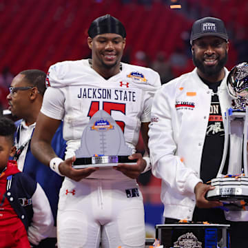 Dec 14, 2024; Atlanta, GA, USA; Jackson State Tigers quarterback Jacobian Morgan (15) and head coach T.C. Taylor and defensive lineman Jeremiah Williams (0) hold trophies after a victory over the South Carolina State Bulldogs in the Celebration Bowl at Mercedes-Benz Stadium. Mandatory Credit: Brett Davis-Imagn Images
