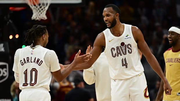 Two basketball players celebrating together while wearing white uniforms.