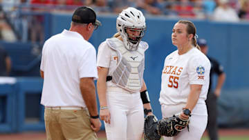 Texas coach Mike White talks with Texa pitcher Mac Morgan (55) and Reese Atwood (14) during Game 2 of the NCAA softball Women's College World Series Championship Series game between the Oklahoma Sooners (OU) and Texas Longhorns at Devon Park in Oklahoma City, Thursday, June 6, 2024. Oklahoma won 8-4.
