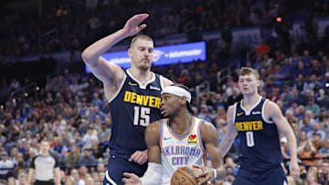 Mar 10, 2025; Oklahoma City, Oklahoma, USA; Denver Nuggets center Nikola Jokic (15) defends a drive by Oklahoma City Thunder guard Shai Gilgeous-Alexander (2) during the second half at Paycom Center. Mandatory Credit: Alonzo Adams-Imagn Images