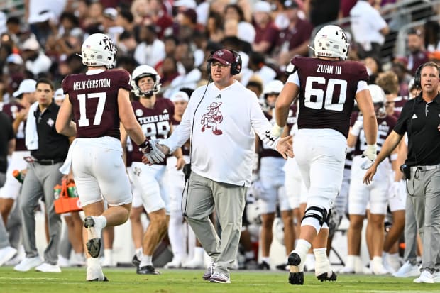 Texas A&M Aggies coach Mike Elko high fives players as they exit the field against the Notre Dame Fighting Irish.