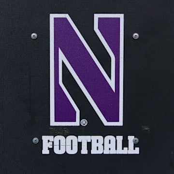 An equipment trailer bearing the Northwestern logo sits on the sidelines of Camp Randall Stadium during a 2017 football game.