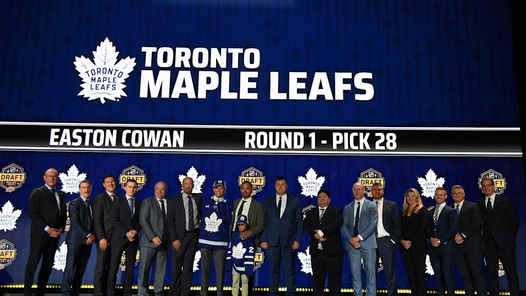 Jun 28, 2023; Nashville, Tennessee, USA; Toronto Maple Leafs draft pick Easton Cowan stands with Leafs staff after being selected with the twenty eighth pick in round one of the 2023 NHL Draft at Bridgestone Arena. Mandatory Credit: Christopher Hanewinckel-Imagn Images